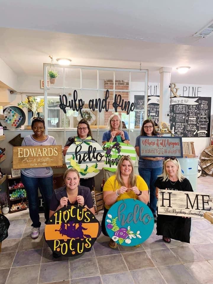 The staff of Georgia Knotek DDS standing with their personally made signs at the Pulp & Pine, a local art studio in Greenfield, IN
